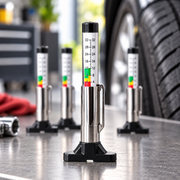 Four chrome tire tread depth gauges in a workshop
